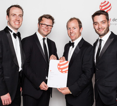 four people with red dot award certificate