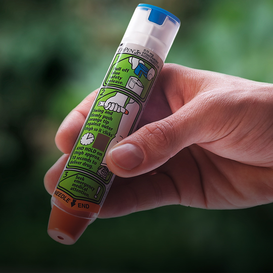close up of hand holding epipen