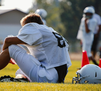 merican football player sitting on ground with helmet off
