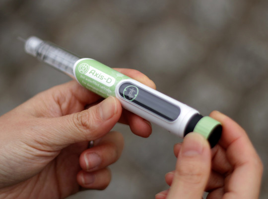 close up of hands adjusting dose on insulin pen