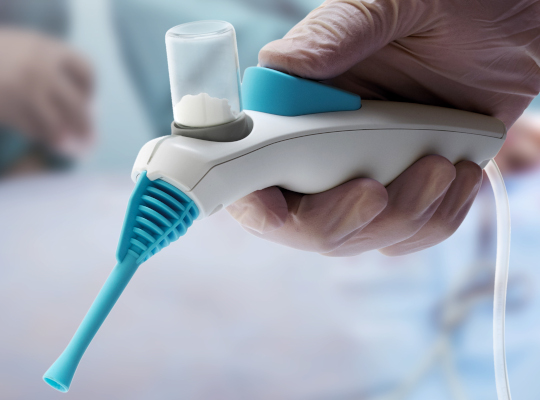 gloved hand holding powder delivery device