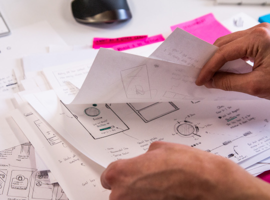 hands flipping through design sketches